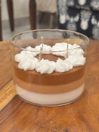 Handcrafted Wickory beeswax candle in a clear glass jar featuring layered caramel-brown and ivory wax, topped with piped white wax resembling whipped cream and multiple braided cotton wicks.
