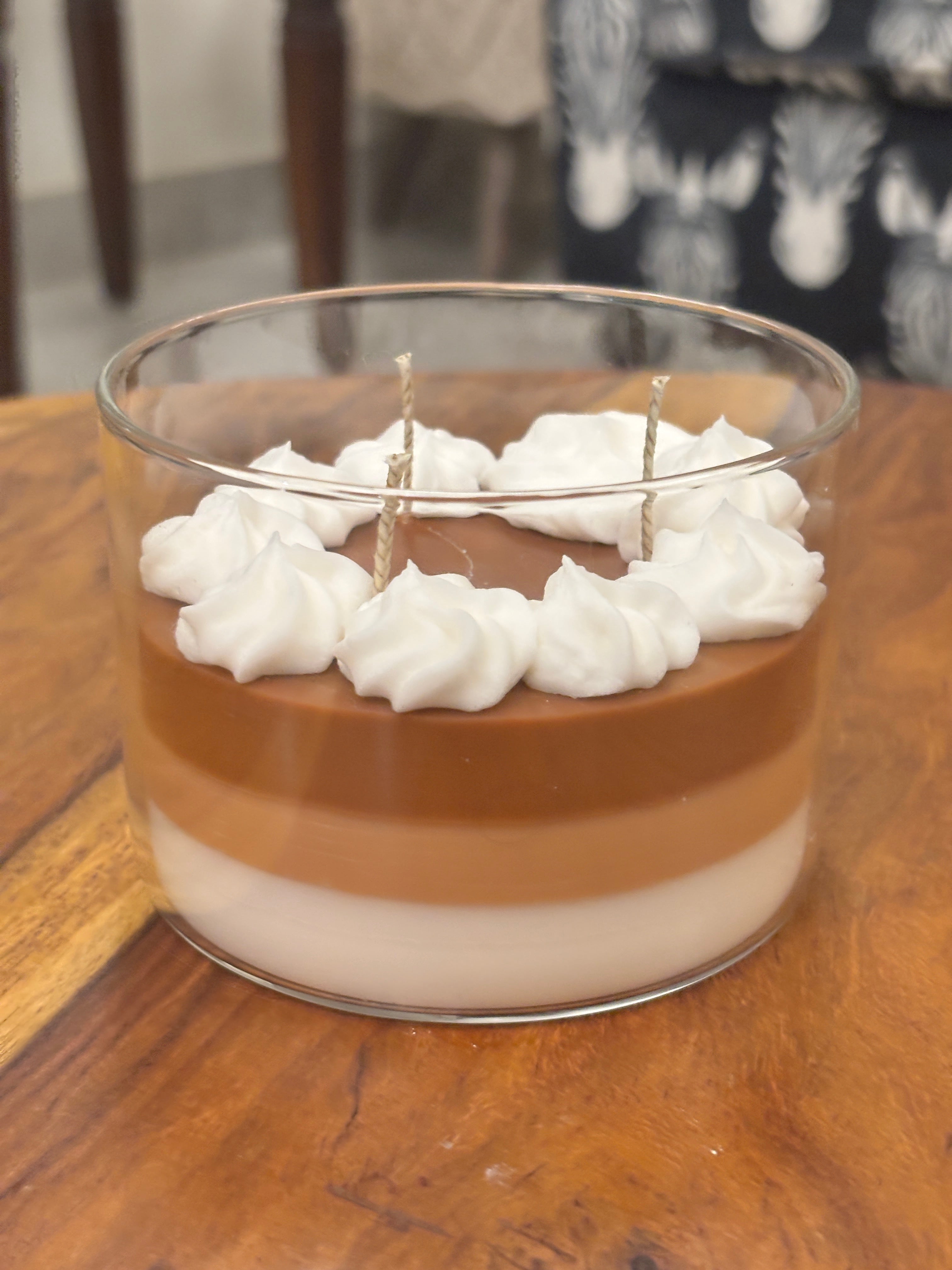 Handcrafted Wickory beeswax candle in a clear glass jar featuring layered caramel-brown and ivory wax, topped with piped white wax resembling whipped cream and multiple braided cotton wicks.