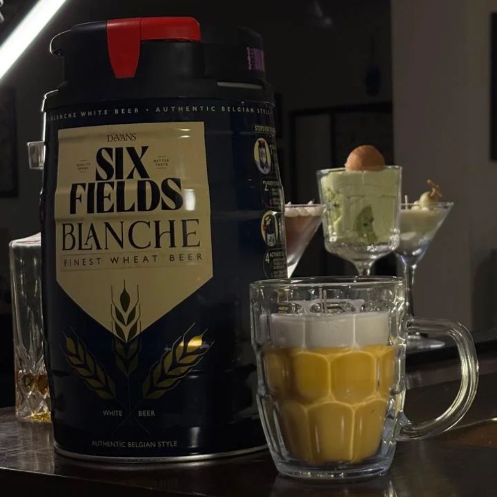 Beer Mug beeswax candle beside a beer keg in a dark bar setting, with martini candles behind