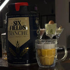 Beer Mug beeswax candle beside a beer keg in a dark bar setting, with martini candles behind