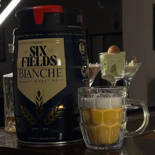 Beer Mug beeswax candle beside a beer keg in a dark bar setting, with martini candles behind