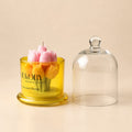 The Bloom Bell: sculpted pink and yellow tulips on a candle in a yellow glass jar, shown beside its glass cloche