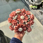 Wickory Blossom Posy held outdoors: dusty rose sculpted beeswax flower candles around a large daisy-style bloom