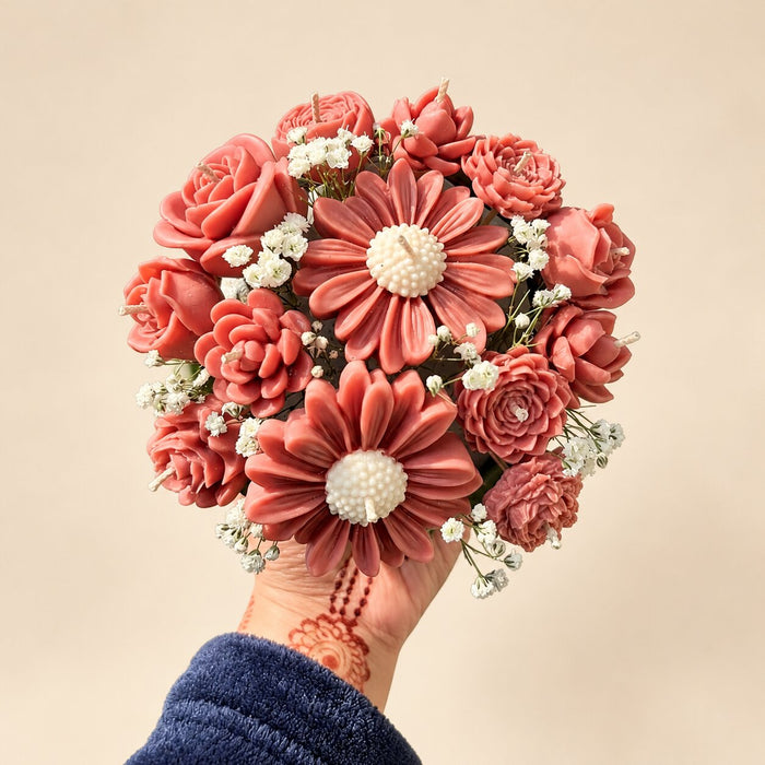 A hand holding the Wickory Blossom Posy: dusty rose sculpted beeswax roses around a large daisy-style bloom, with small white filler flowers
