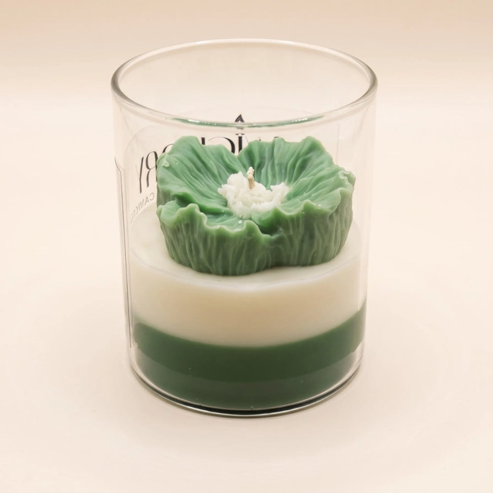 The Blush Petal in green, side view: a sculpted green flower on ivory and green layered wax in a glass jar