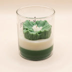 The Blush Petal in green, side view: a sculpted green flower on ivory and green layered wax in a glass jar