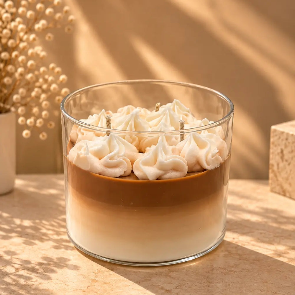 The Café Aura coffee-inspired candle in a glass jar with layered coffee-colored wax and whipped cream topping
