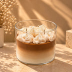 The Café Aura coffee-inspired candle in a glass jar with layered coffee-colored wax and whipped cream topping