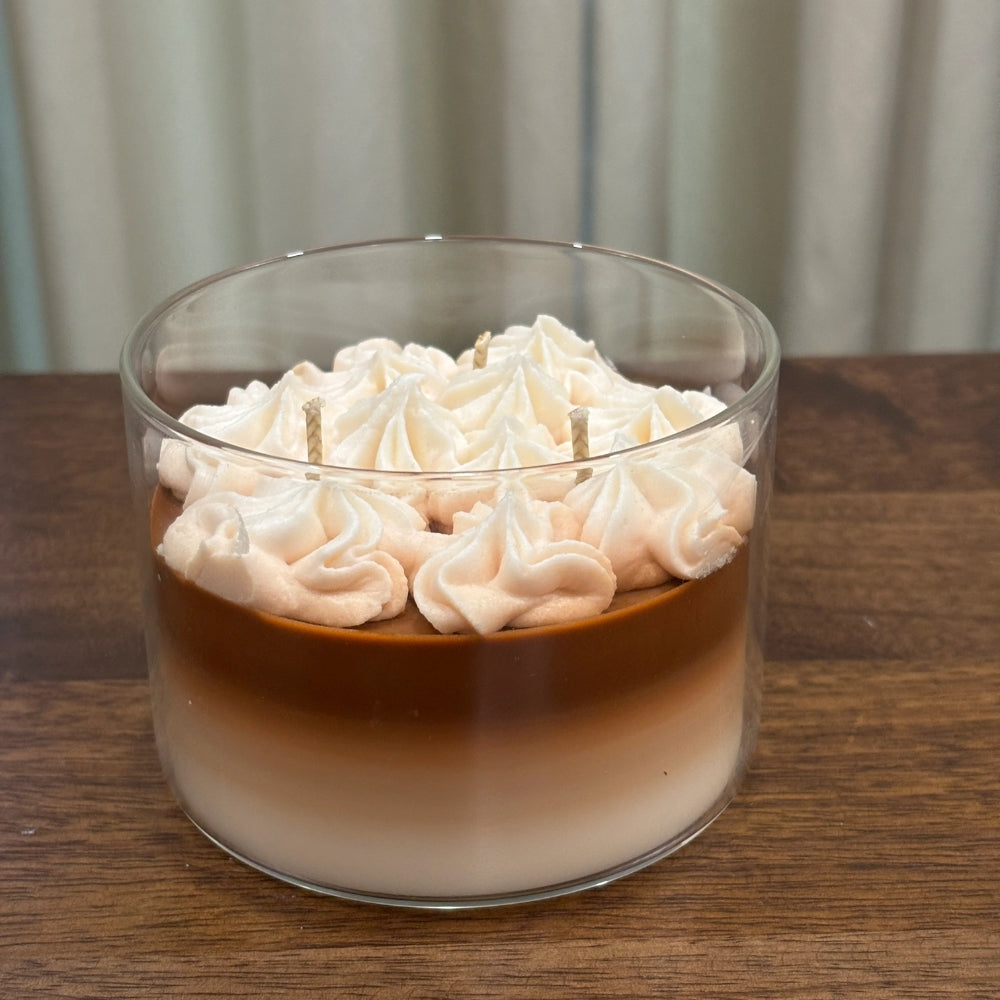 The Café Aura coffee-inspired candle in a glass jar with layered coffee-colored wax and whipped cream topping