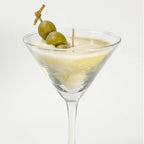 Close-up of the Dirty Martini candle: ivory wax and sculpted green olives on a wooden skewer in a martini glass
