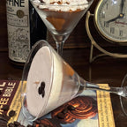 Espresso Martini candles styled with coffee beans, a coffee book and a vintage clock, one glass tipped to show the creamy top