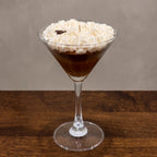 Espresso Martini beeswax candle with a whipped top and a coffee bean in a martini glass, on a wooden table