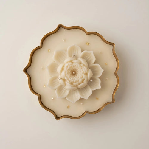 Close-up of the Glittering Urli with Lotus: a sculpted ivory lotus on beeswax flecked with gold flakes, in a gold-edged urli