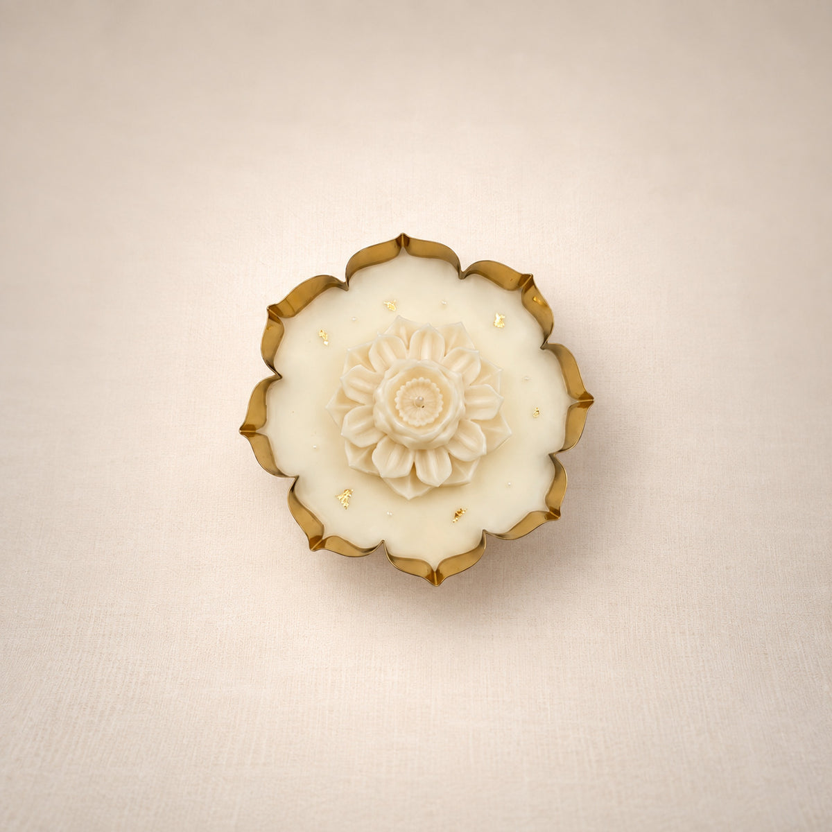 Glittering Urli with Lotus, top view: a gold-edged urli filled with ivory beeswax and crowned with a sculpted ivory lotus