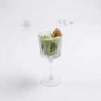 Kiwi Colada candle in a stemmed glass on a white background