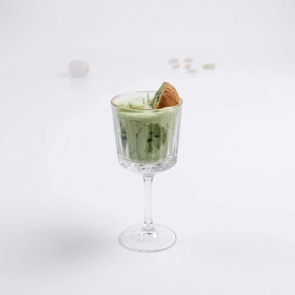 Kiwi Colada candle in a stemmed glass on a white background