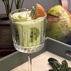 Kiwi Colada candle styled with a coconut on a tray, kiwi slices pressed against the glass