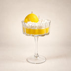 Limoncello beeswax candle: yellow wax with a whipped top and a sculpted lemon in a stemmed coupe glass