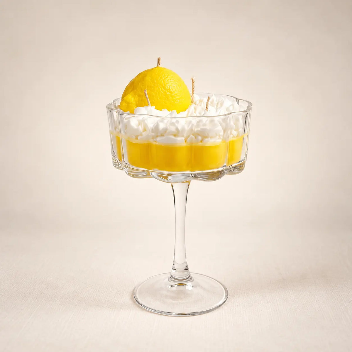 Limoncello beeswax candle: yellow wax with a whipped top and a sculpted lemon in a stemmed coupe glass