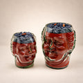 The Old Monk: two face-shaped glass jars with red wax and a dark purple whipped wax top