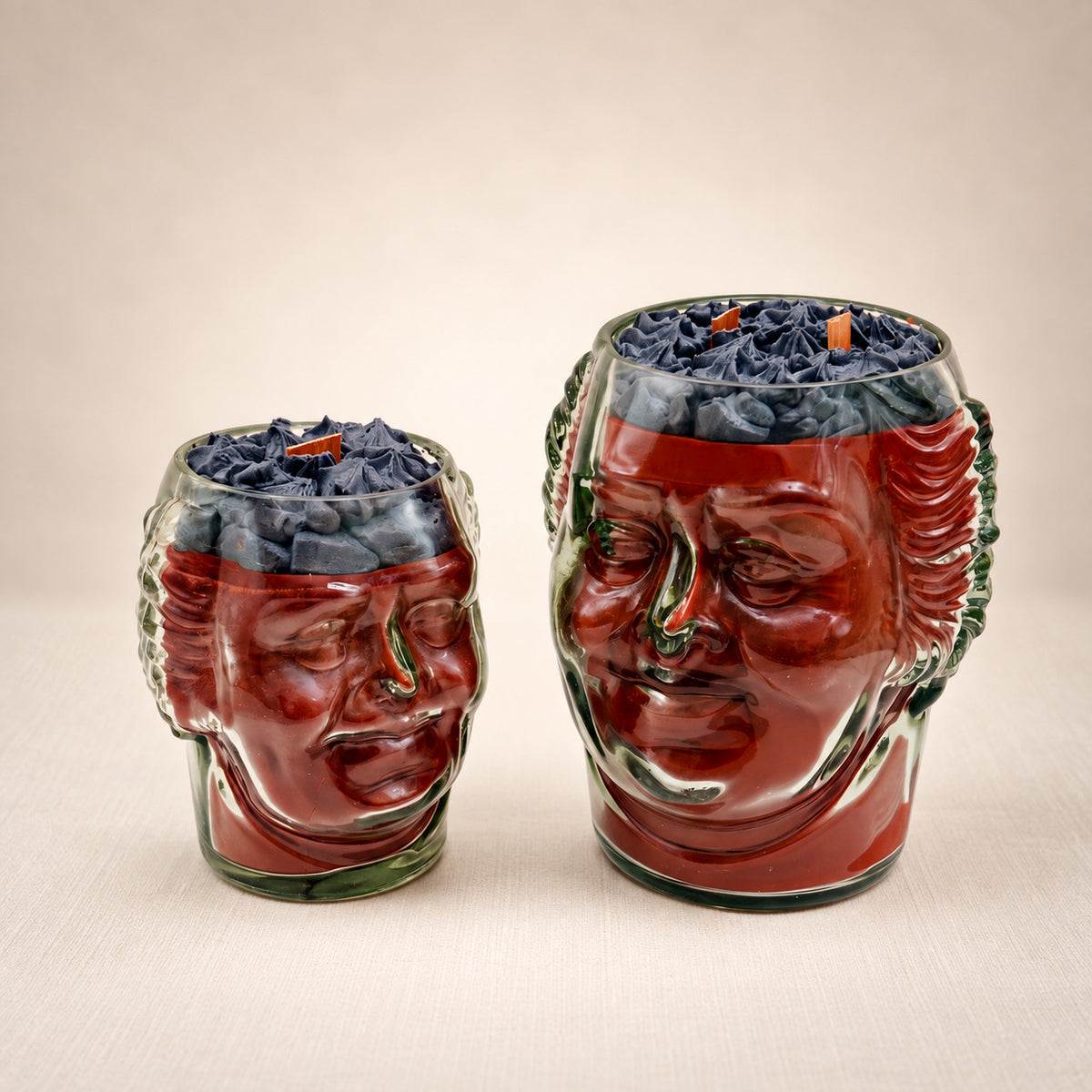 The Old Monk: two face-shaped glass jars with red wax and a dark purple whipped wax top