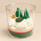 The Snowy Spruce: green, red and ivory layered wax with whipped white swirls, sculpted trees, a holly wreath and a gingerbread figure, in a clear jar