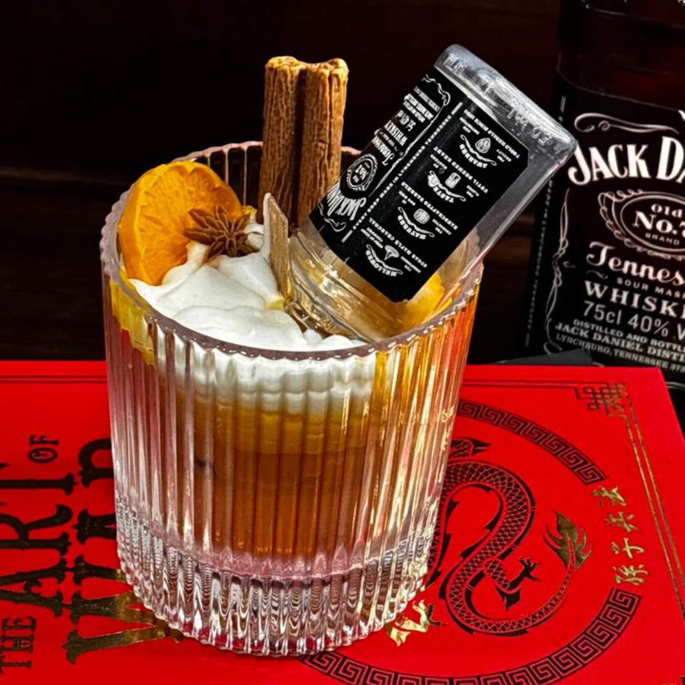 Whiskey Sour candle on a red book, with a whiskey bottle behind