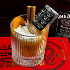 Whiskey Sour candle on a red book, with a whiskey bottle behind